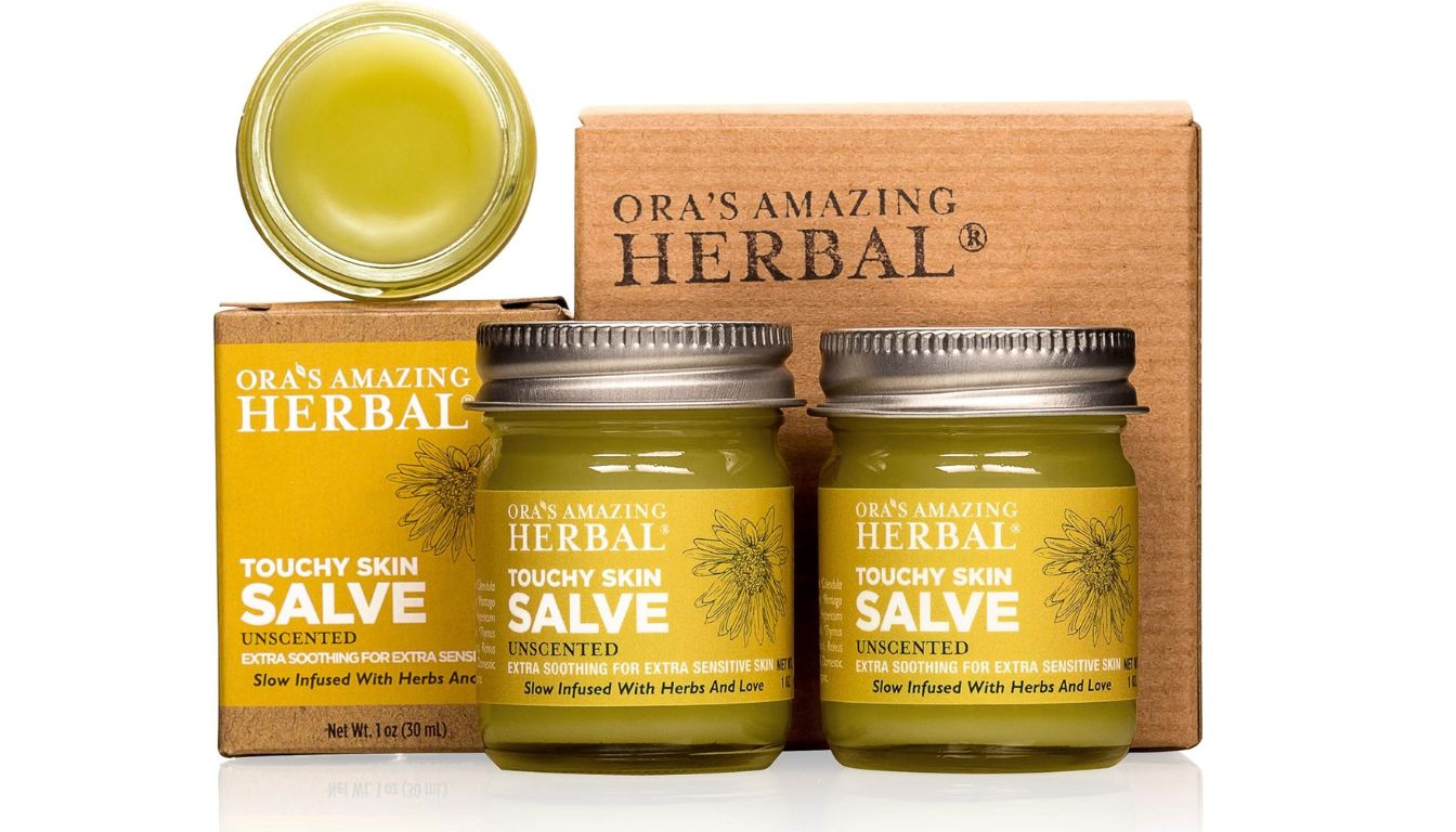 Two jars of Ora's Amazing Herbal Touchy Skin Salve with yellow labels and open jar showing greenish salve.